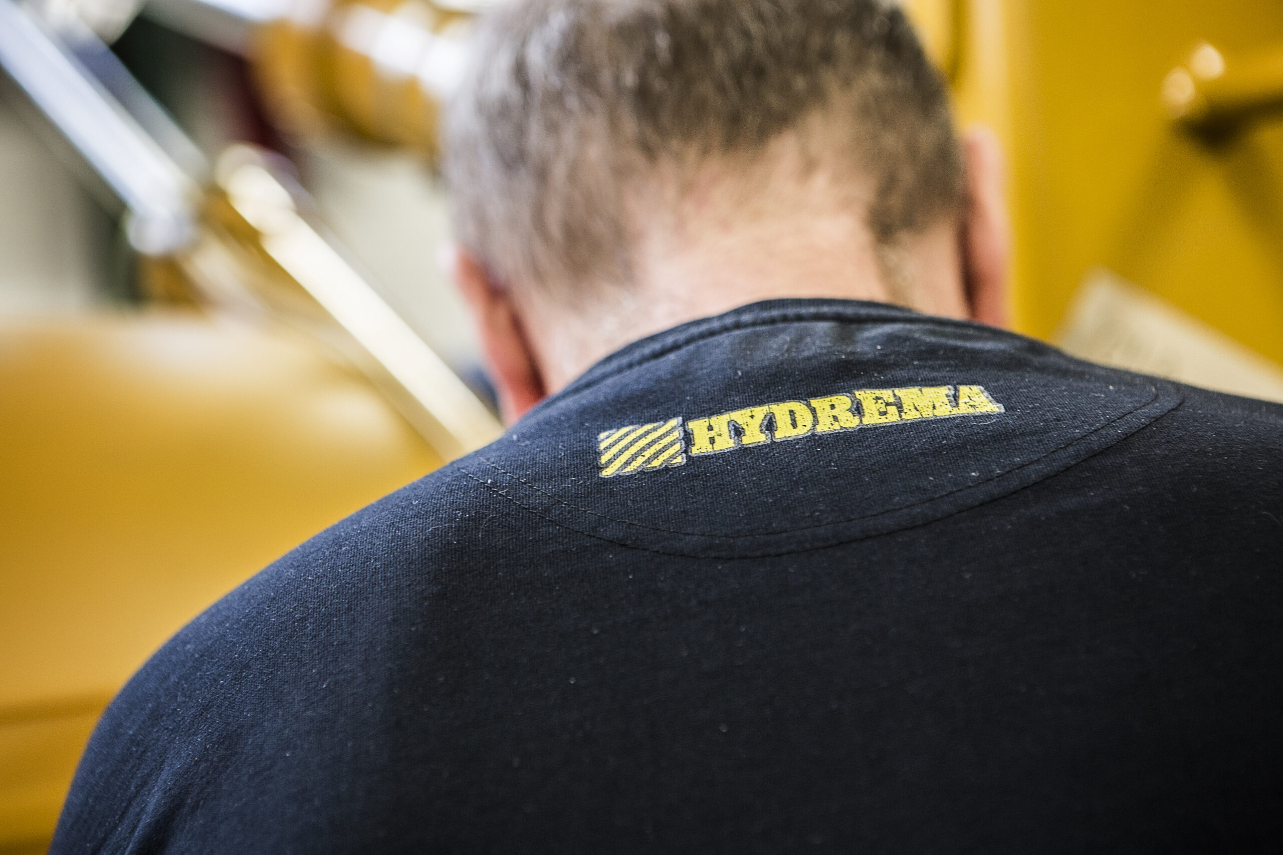 hydrema logo on shirt on mans neck